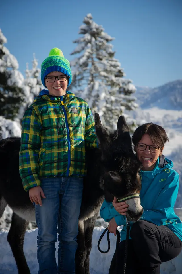 Junge reitet auf Esel im Winter, begleitet von Helene